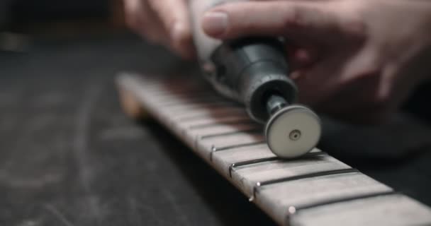 Geigenbauer poliert neue Bünde auf dem Griffbrett der Gitarre in der Instrumentenwerkstatt, 4k 60fps Prores HQ - Filmmaterial, Video