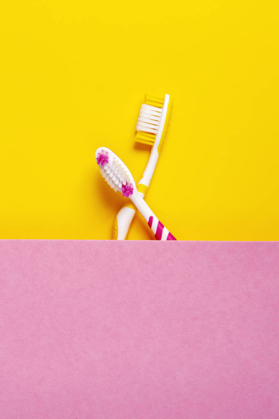 toothbrushes in two colors, yellow and pink. 2 color background. Copy space. - Photo, Image