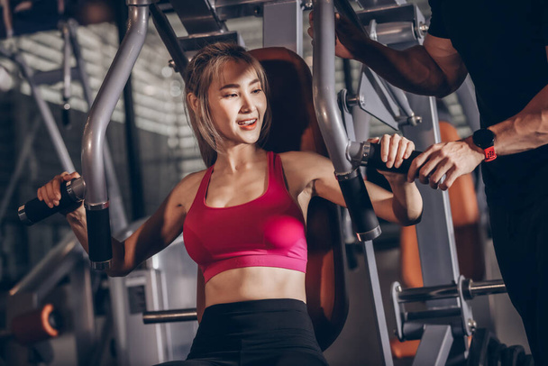 Fiatal ázsiai nő visel aktív kopás, amelynek sport edzés gyakorló gép egy edzőteremben. - Fotó, kép