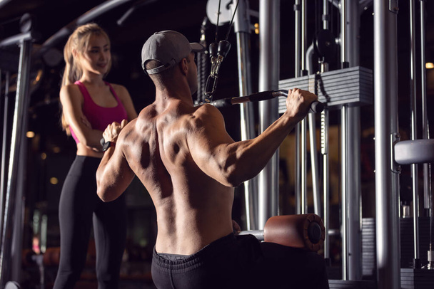 Um forte fisiculturista homens atléticos bombeando-se músculos por máquina de exercícios durante o exercício no ginásio. - Foto, Imagem
