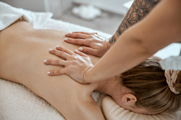 Profissional mestre de massagem confiante está fazendo procedimentos para mulher caucasiana no armário moderno minimalista - Foto, Imagem