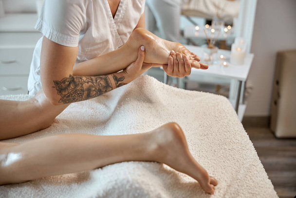 Profesional seguro de masaje maestro está haciendo los procedimientos a la mujer caucásica en el gabinete moderno minimalista - Foto, imagen