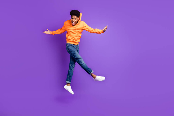 Full body photo of brown haired young dark skin happy man wear jeans jump up hands winner isolated on purple color background - Foto, Imagem