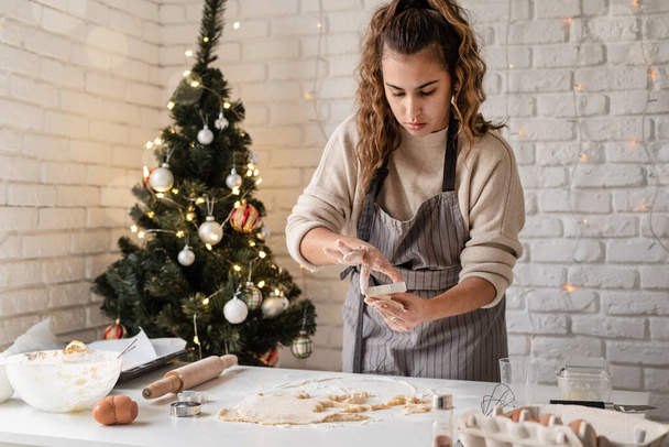 Merry christmas and happy new year. Smiling woman in the kitchen baking christmas cookies - Photo, Image