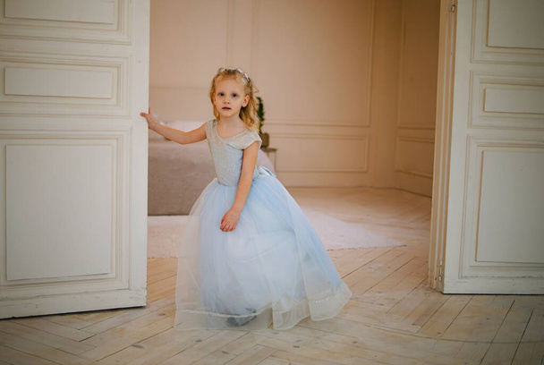 schattig klein meisje in een mooie jurk in de zon kamer licht - Foto, afbeelding