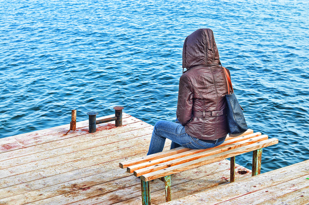 Figura solitária de uma menina no cais no lago no outono
 - Foto, Imagem