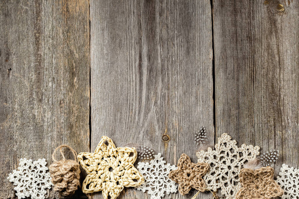 Fond en bois d'hiver ou de Noël avec des étoiles au crochet et bordure flocons de neige. Décorations de Noël faites à la main en matériaux naturels. Vue de dessus, plan plat. - Photo, image