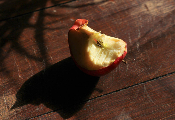 angebissener Apfel, Stumpf auf dunklem Holzgrund  - Foto, Bild