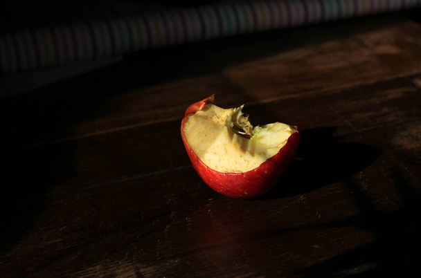 pomme mordue, stub sur un fond en bois foncé  - Photo, image