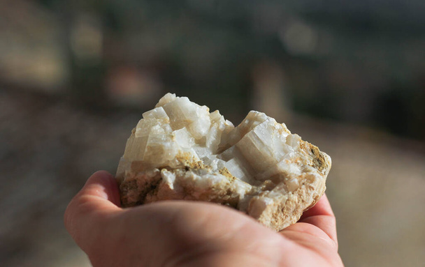 Mineral de piedra acostado en una mano femenina sobre el fondo de otras piedras  - Foto, Imagen