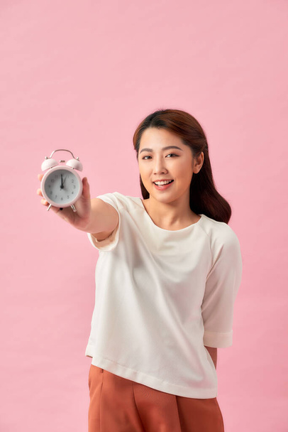 Joven asiática mujer sobre aislado rosa fondo celebración vintage reloj despertador - Foto, Imagen