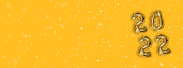 2022 altın folyo balonları dekorasyon ve sarı arka planda fotokopi alanı olan Noel karı. Yeni yıl konsepti - Fotoğraf, Görsel