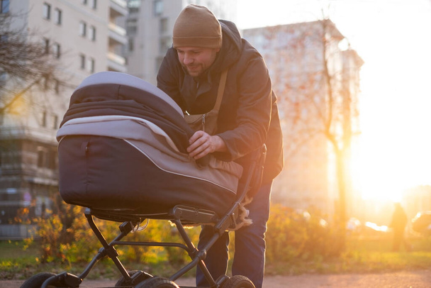 Glücklicher junger Vater mit Kinderwagen beim Spaziergang in der Natur - Foto, Bild