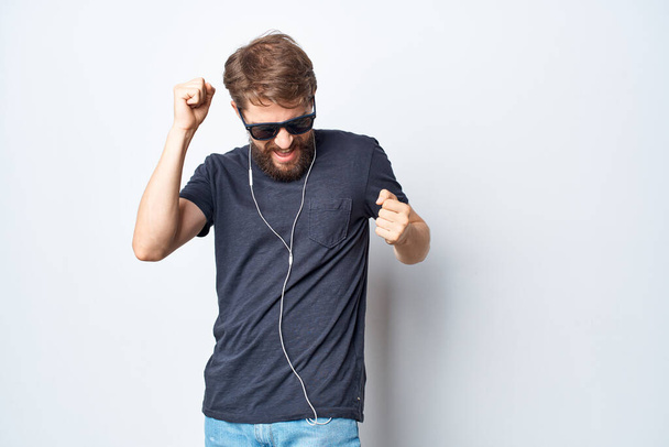 handsome man in a black t-shirt music in headphones movement light background - Фото, зображення