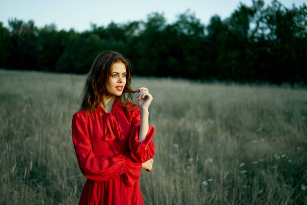 Kaunis nainen punainen mekko alalla luonto poseeraa maisema - Valokuva, kuva