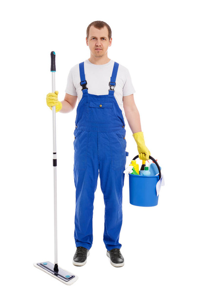 full length portrait of handsome man cleaner in blue uniform posing with mop and bucket with cleaning equipment isolated on white background - 写真・画像