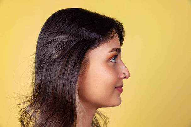Side view of young beuatiful girl, student in bright red top isolated on yellow studio backgroud. - Photo, image