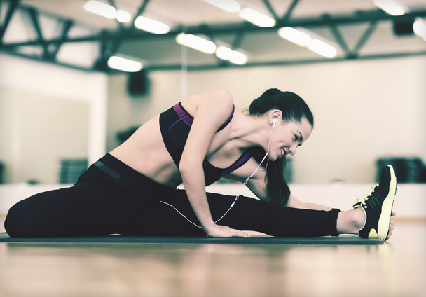 smiling woman stretching on mat in the gym - Fotografie, Obrázek