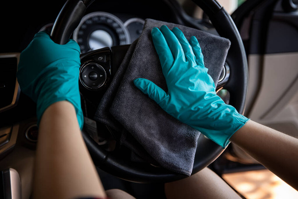 zöld kesztyűt viselő nők tisztítása kormánykerék autó mikroszálas szürke tisztító autó koncepció  - Fotó, kép