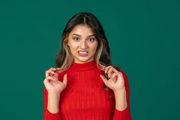 Close-up portrait of young beuatiful girl, student in bright red sweater isolated on green studio backgroud. - Φωτογραφία, εικόνα