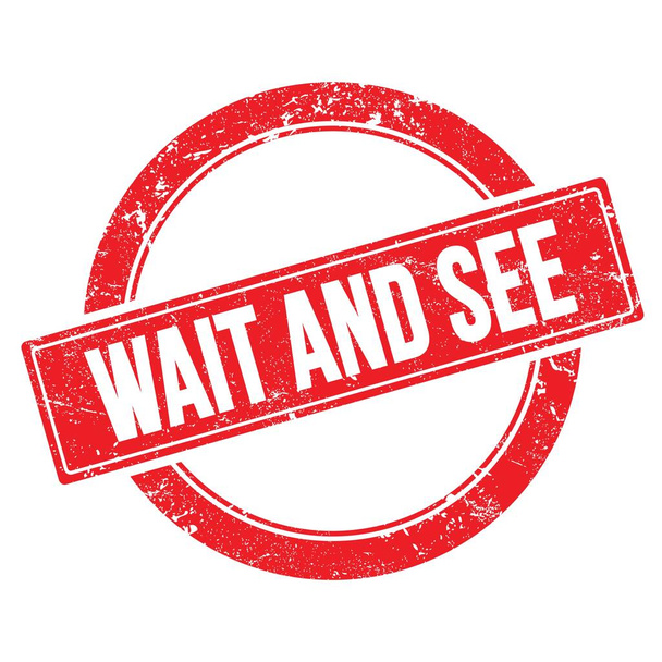 Текст WAIT AND SEE на червоній гранжевій круглої вінтажної марки
. - Фото, зображення