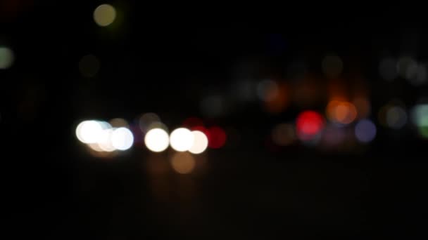 Ночью на темном размытом фоне скользит боке. Круглый красочный боке сияет от автомобильных огней на городской улице. Не в фокусе с расплывчатым. Несфокусированные огни города. Пробки на дорогах. Абстрагируясь - Кадры, видео