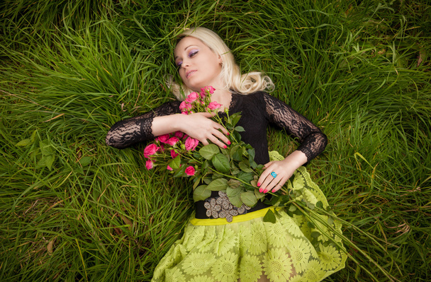Portret van vrouw met rozen slapen op veld - Foto, afbeelding