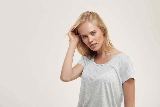 Young confident european girl looking at camera. Beautiful blonde female teenager with blue eyes wear white t-shirt. Isolated on white background. Studio shoot. Copy space - Photo, Image
