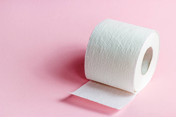 Λευκό ρολό χαρτί τουαλέτας σε ανοιχτό ροζ φόντο με χώρο αντίγραφο. - Φωτογραφία, εικόνα