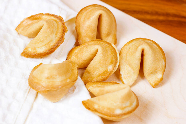 Verse gebakken gele Chinese gelukskoekjes op lichte achtergrond. - Foto, afbeelding
