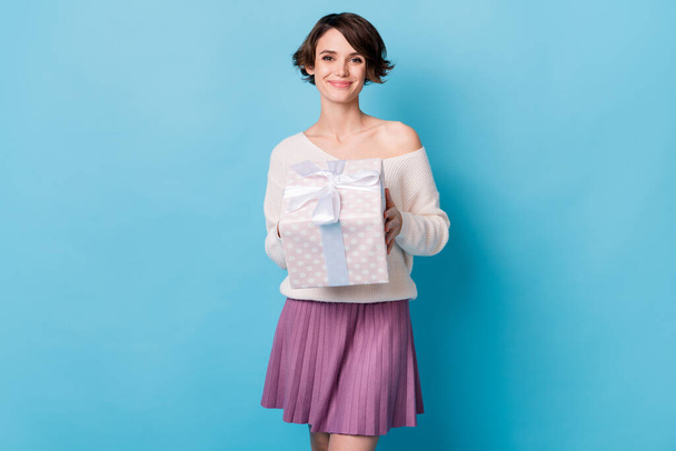 Photo portrait of woman holding wrapped gift box isolated on pastel blue colored background - Foto, afbeelding