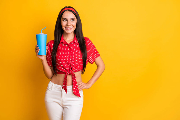 Photo of sweet shiny young lady wear red shirt holding soda glass looking empty space isolated yellow color background - Fotografie, Obrázek