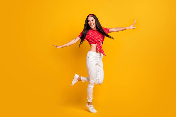 Full length photo of cute shiny young lady wear red shirt dancing hands arms sides isolated yellow color background - Фото, изображение