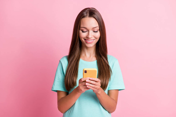 Photo portrait of smiling woman keeping smartphone using app smiling isolated on pastel pink color background - Фото, изображение