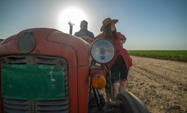 Una giovane coppia di contadini sposati è venuta sul campo con un trattore per visitare i raccolti. - Foto, immagini