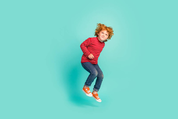 Full body photo of funny little boy jump wear shirt jeans sneakers isolated on blue background - Foto, afbeelding