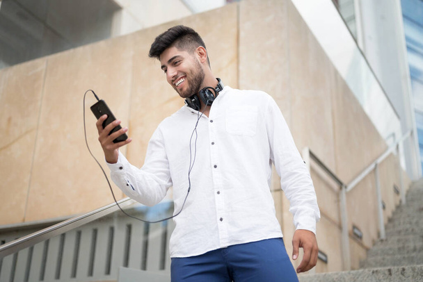 Joven hombre hispano guapo usando teléfono inteligente al aire libre. - Foto, imagen