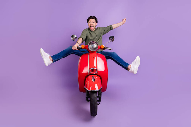 Full body photo of cool cheerful crazy young man ride bike speed winner isolated on purple color background - Фото, зображення