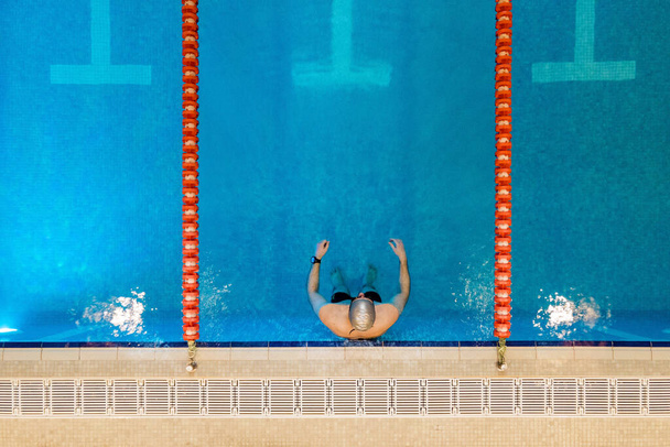 空中,プロの水泳選手のドローントップダウンビュー,スイミングプールで泳ぐ.  - 写真・画像
