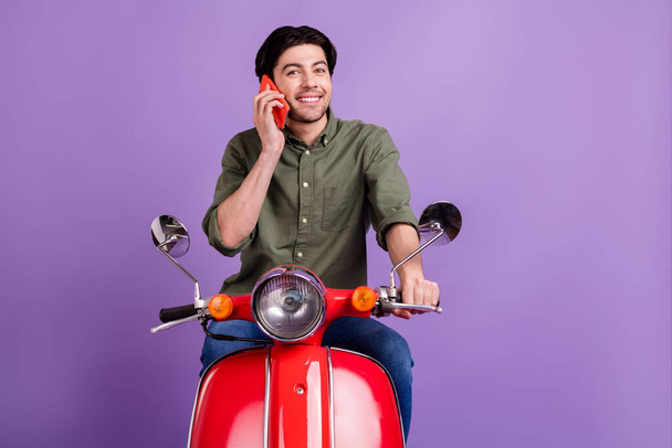 Foto de soñador joven feliz hombre cogido de la mano teléfono hablar disfrutar de sonrisa fresca aislado en el fondo de color púrpura - Foto, Imagen