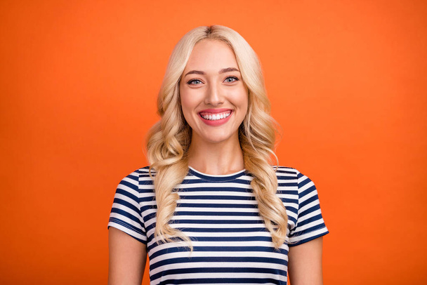 Photo portrait smiling blonde woman wearing striped t-shirt isolated bright orange color background - Foto, Imagen