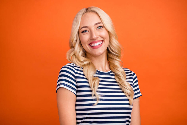 Portrait of attractive cheerful girl wearing striped tshirt beaming smile isolated over vibrant orange color background - Foto, Imagen