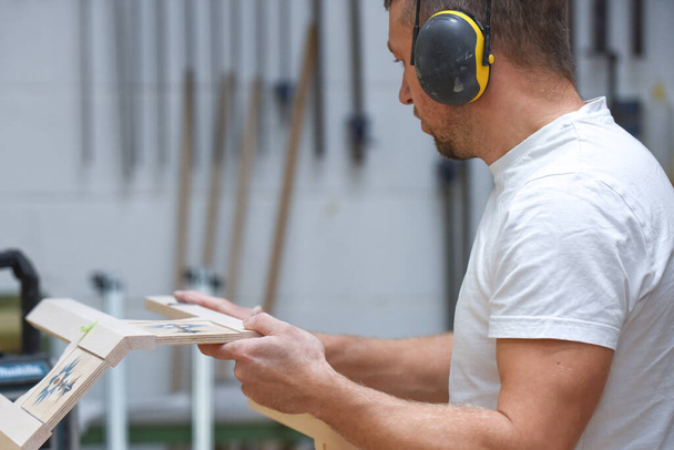 Um homem está fazendo móveis sob medida em uma oficina de madeira mostrando o processo de construção - Foto, Imagem