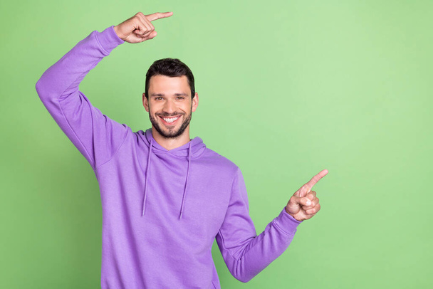 Photo of young man happy positive smile point fingers empty space ad promo recommend isolated over green color background - Valokuva, kuva