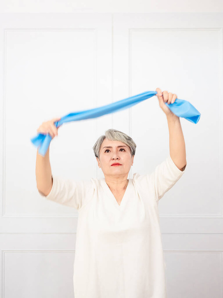 Senior asian woman doing exercises with resistance band at home. - Photo, Image