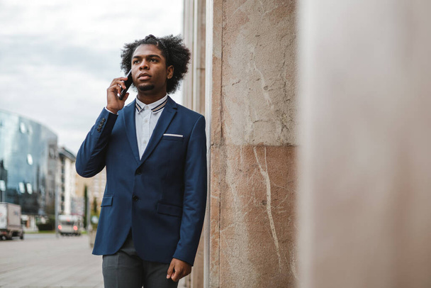 stylish african american businessman talking on the phone outdoors - Fotó, kép