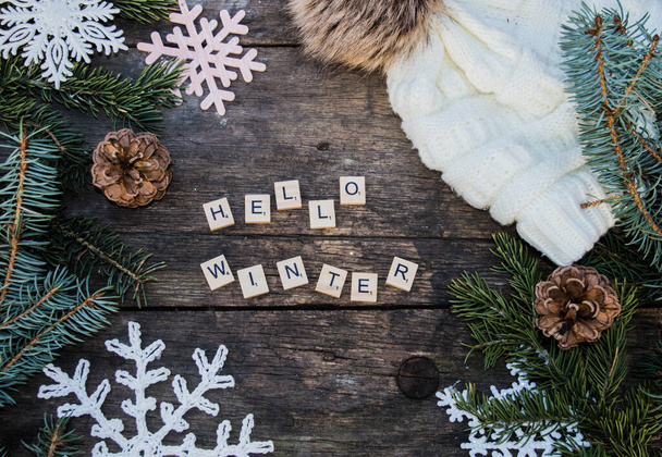 crochet snowflake ornaments on wooden ground with winter slogans and fir branch and cones and a knitted bobble hat background - Photo, Image