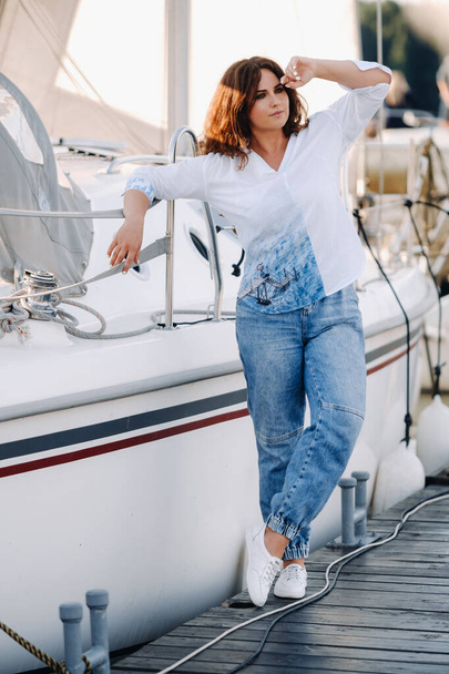 a happy woman with long hair stands on the pier near the yacht. - Foto, afbeelding