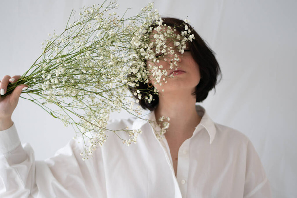 portrait of young beautiful woman with white bouquet in studio - Fotó, kép