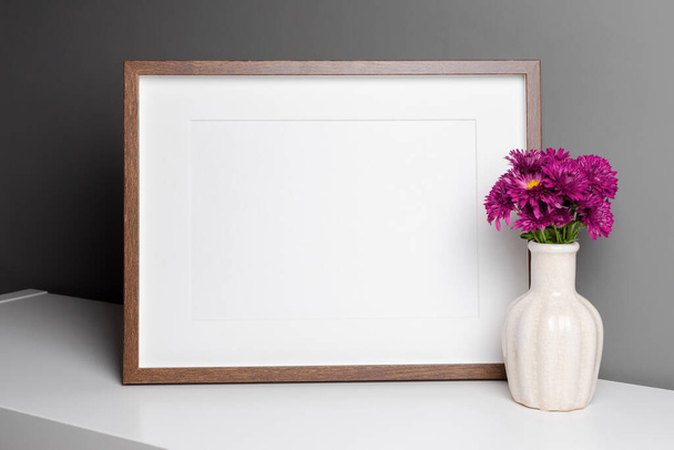 Blank landscape frame mockup over grey wall with fresh chrysanthemum flowers. - Foto, Imagen